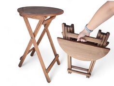 a wooden table and stool are shown with one hand on the chair, while the other is reaching for it