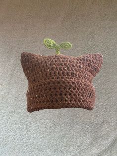 a crocheted pillow with a small plant on the front and back of it