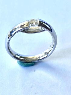 a white gold ring with a diamond in the center on a light blue tablecloth