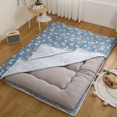 a large mattress is laying on the floor next to a table and potted plant