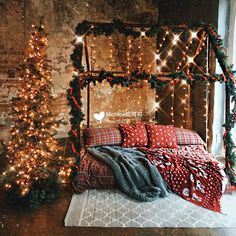 a bed covered in blankets and lights next to a tree with christmas decorations on it