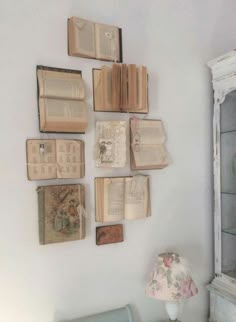 several books are hanging on the wall next to a chair and table with a lamp