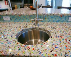 a stainless steel sink in a kitchen with colorful speckles on the counter top