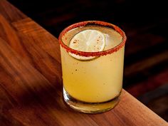 a close up of a drink on a wooden table with a slice of lemon in it