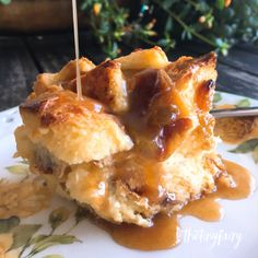 a piece of bread with caramel sauce on it sitting on a plate next to a potted plant