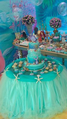 the table is set up for a little mermaid birthday party with decorations and desserts