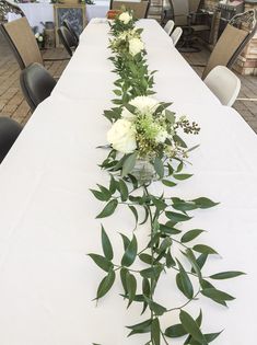 a long table with flowers and greenery on it