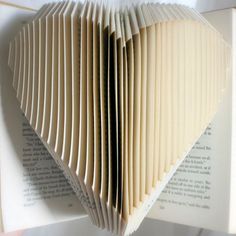 an open book with folded pages in the shape of a heart sitting on top of each other