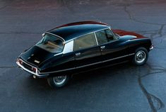 an old black car parked in a parking lot