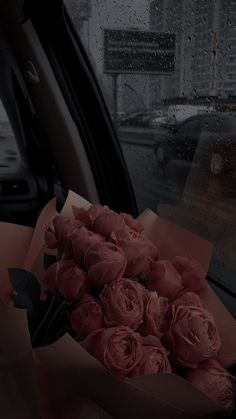 a bunch of roses sitting in the back seat of a car on a rainy day