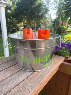 a metal bucket filled with orange cups sitting on top of a wooden table