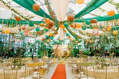 an indoor wedding venue decorated with orange and green paper lanterns, hanging from the ceiling