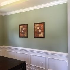 two framed pictures hang on the wall above a table