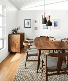 a dining room table with chairs and pictures on the wall above it, along with an area rug