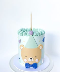 a birthday cake with a bear on it and a blue bow tie around the top