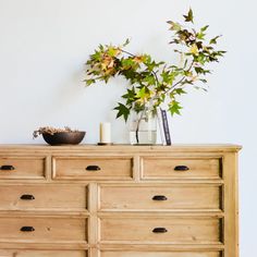 a wooden dresser topped with lots of drawers next to a vase filled with flowers on top of it