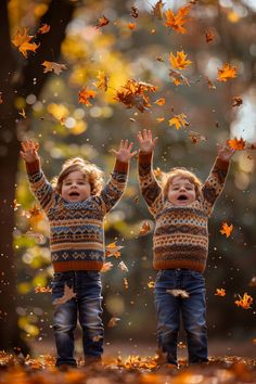 two young children playing with leaves in the air