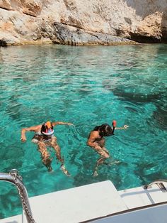 two people are swimming in the clear blue water