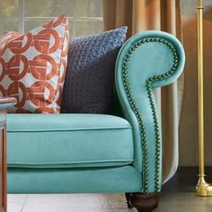 a blue couch sitting in front of a window next to a lamp on a table