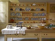 an old fashioned kitchen with many plates and bowls on the counter top in front of it