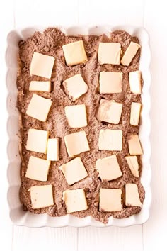 a pan filled with brownies and cheese on top of a white table next to a knife