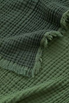 a green blanket with fringes laying on top of it