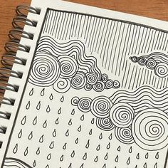 a spiral notebook with an image of a rain and clouds on it, sitting on top of a wooden table