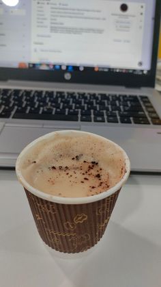 a cup of coffee sitting in front of a laptop