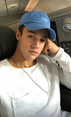 a young man wearing a blue hat sitting in an airplane