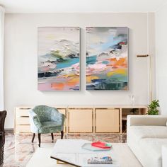 two paintings on the wall above a coffee table in a living room with white furniture