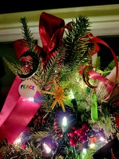 a decorated christmas tree with red ribbon and ornaments on it's branches, lite up by lights