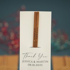 two wooden pencils sitting on top of a white card with the words thank you