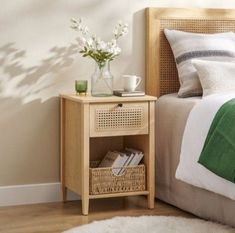 a bed room with a neatly made bed and a basket on the nightstand next to it