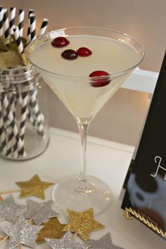 a martini with cherries in it sitting on a table next to a book and decorations