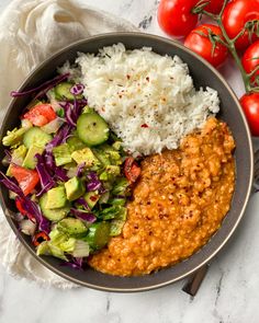 a bowl filled with rice, beans and vegetables next to some tomatoes on the side