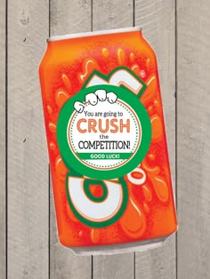 a can of crush the competition on a wooden fence with an orange and green label