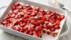 a white dish filled with cake covered in strawberries