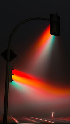 a traffic light that is red, yellow and green in the night sky with rainbow streaks on it