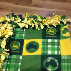 a green and yellow plaid blanket on the floor with some ribbons around it that are tied together