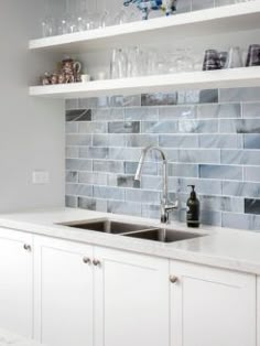 a kitchen with white cabinets and blue tile backsplashes on the countertops