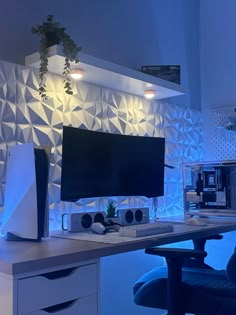 a desk with a computer monitor and keyboard on it in front of a blue wall