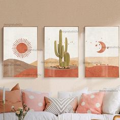 three cactus paintings hanging on the wall above a white couch in a living room with pink pillows