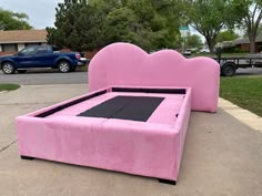 a pink bed sitting on top of a sidewalk