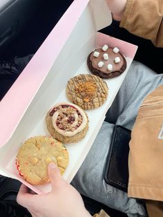 a person holding a box filled with different types of cookies