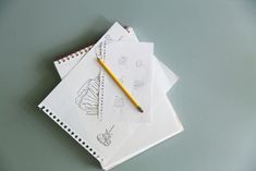 three notebooks with drawings on them sitting next to a yellow pencil and eraser