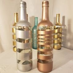 three bottles are lined up on a white tablecloth with gold and silver foil strips