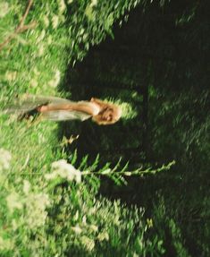 a woman is in the grass with her hair flying through the air and looking up