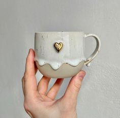 a hand holding a coffee cup with a heart on the inside and white glaze