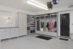 a large walk in closet filled with lots of white cupboards and coats hanging on the walls