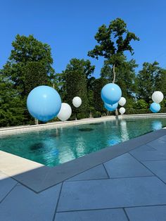 blue and white balloons floating in the air near a swimming pool